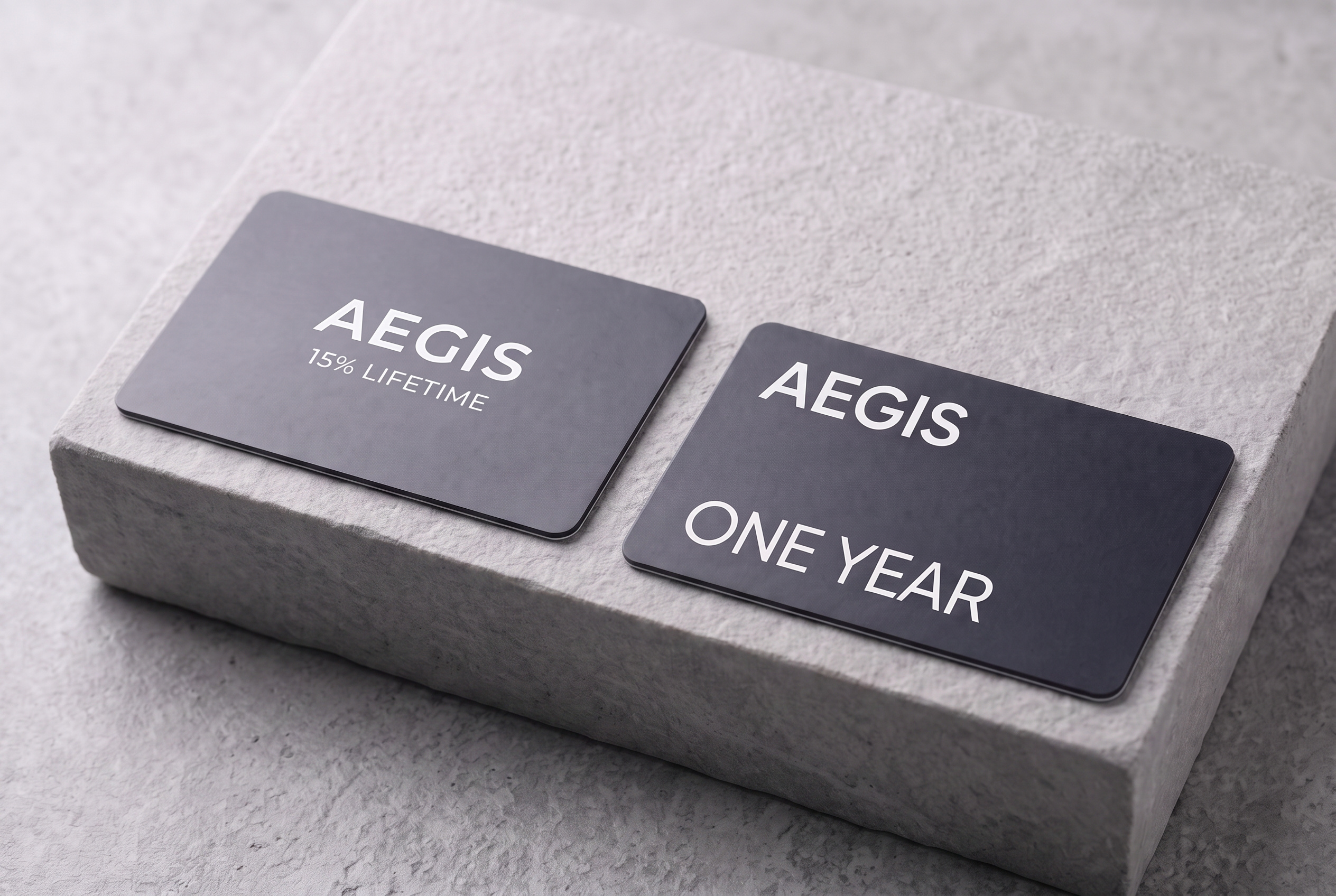 Two matte black Aegis cards on stone. One reads 15% Lifetime. The other reads One Year.